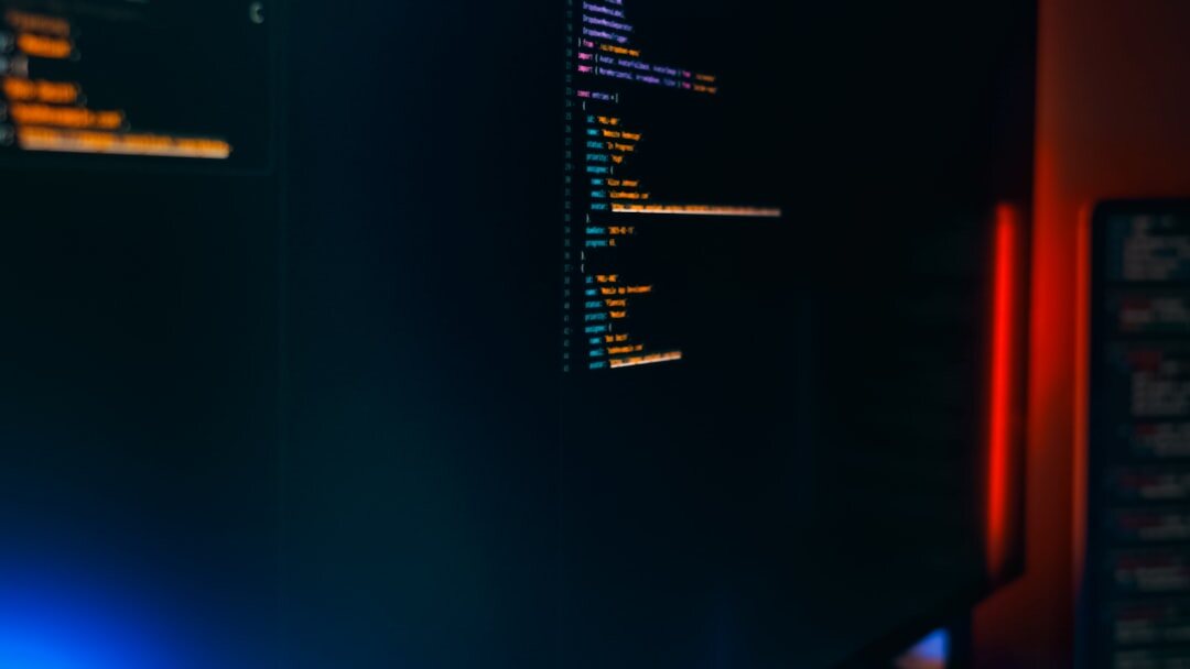 Person working on laptop with code and data on screen in modern workspace